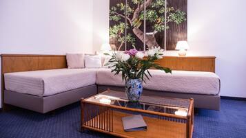 Una habitación de hotel moderna con sofá seccional, una mesa de centro de vidrio y un cuadro grande en la pared.