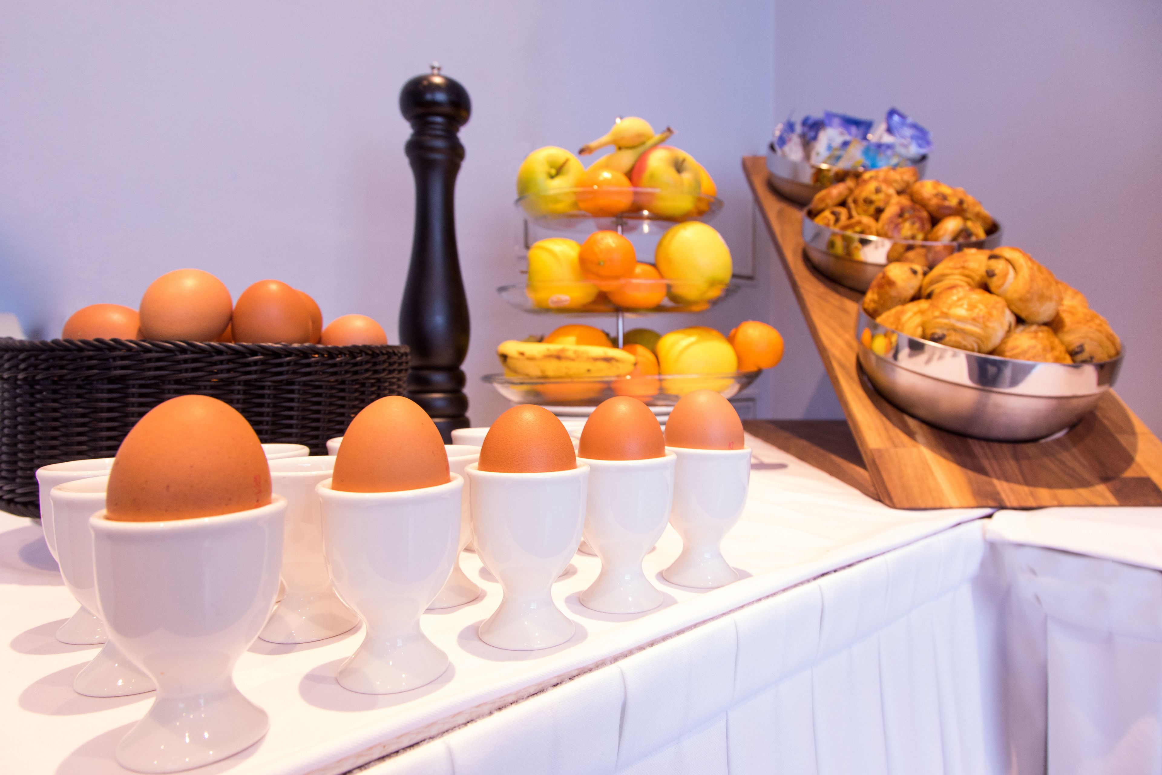 A breakfast buffet with eggs, fruits, and pastries.