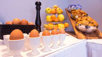 A breakfast buffet with eggs, fruits, and pastries.