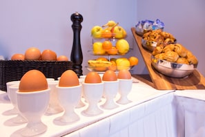 Een ontbijtbuffet met eieren, fruit en gebak.