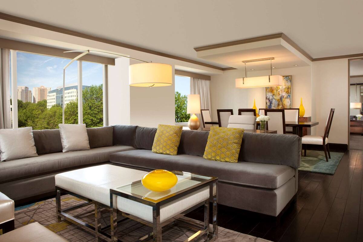 A modern living room with a sectional sofa, a glass coffee table, and a dining area with a table and chairs.