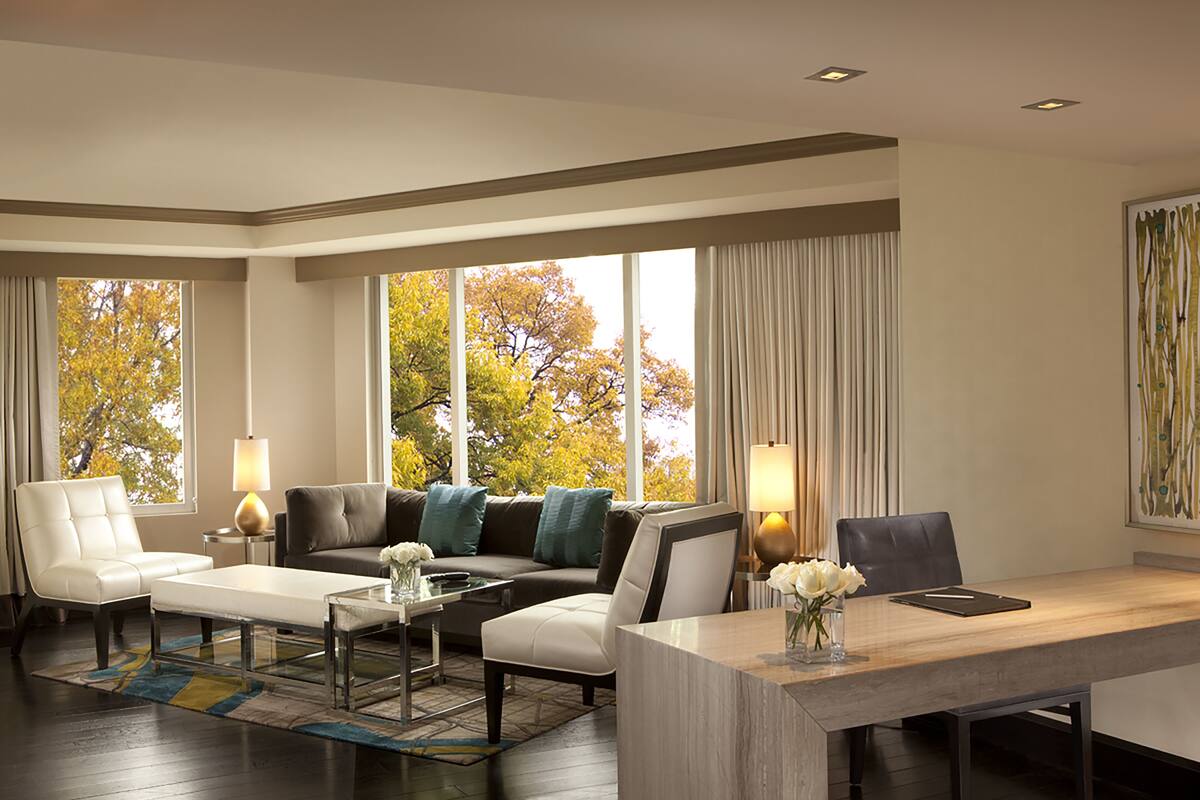 A modern living room with a sofa, armchair, coffee table, and a dining table with chairs.