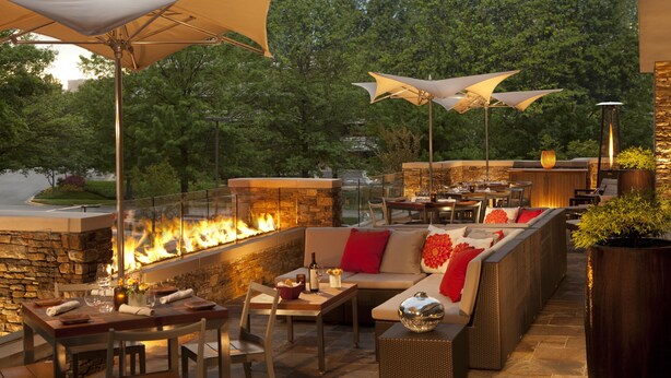 Un patio al aire libre con chimenea de piedra, zona de estar y mesas de comedor.
