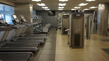 A gym with treadmills, weight machines, and a TV on the wall.