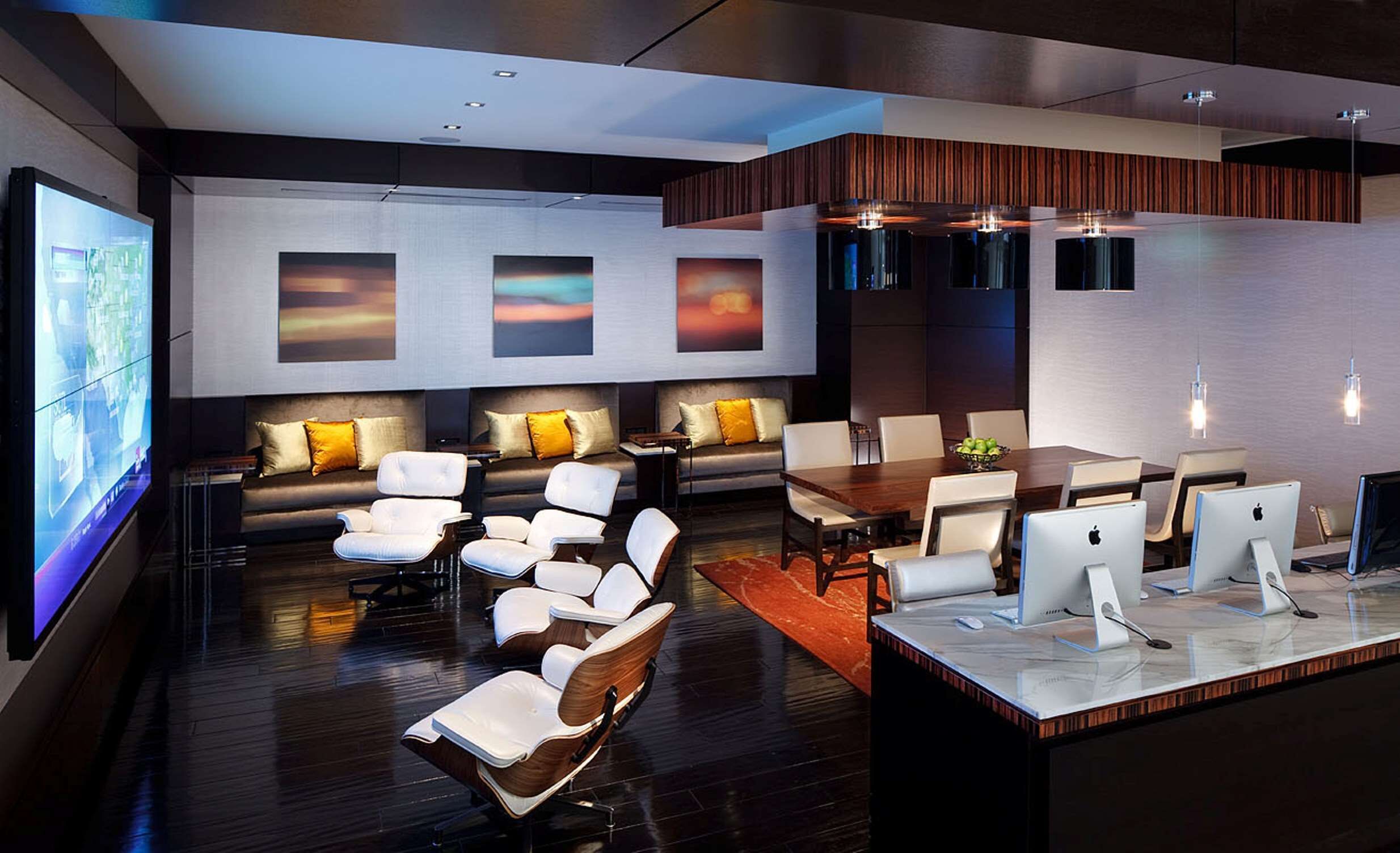 A modern hotel lobby with a seating area, a reception desk, and a large screen displaying a cityscape.