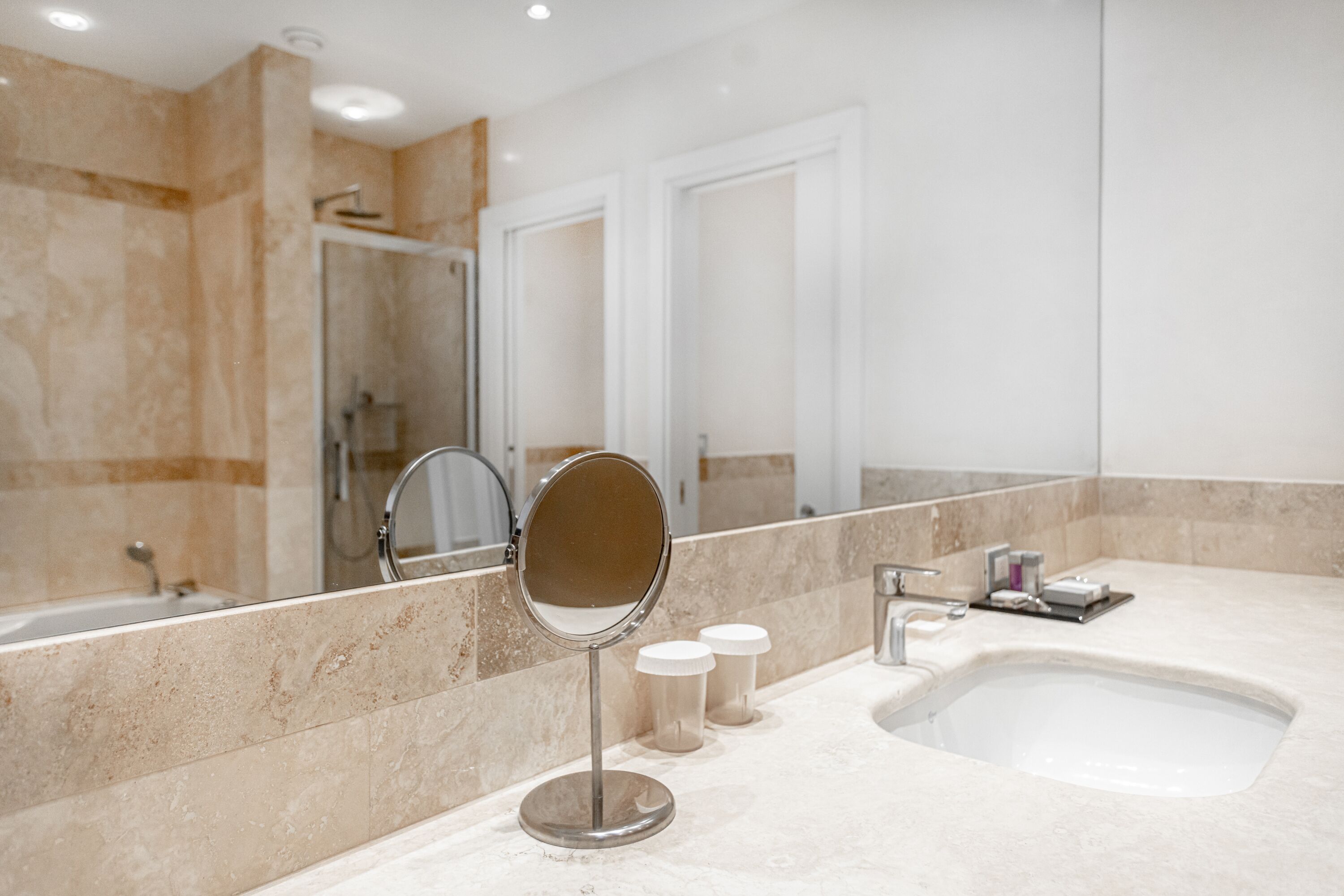 A modern bathroom with a large mirror, a sink, and a shower area.