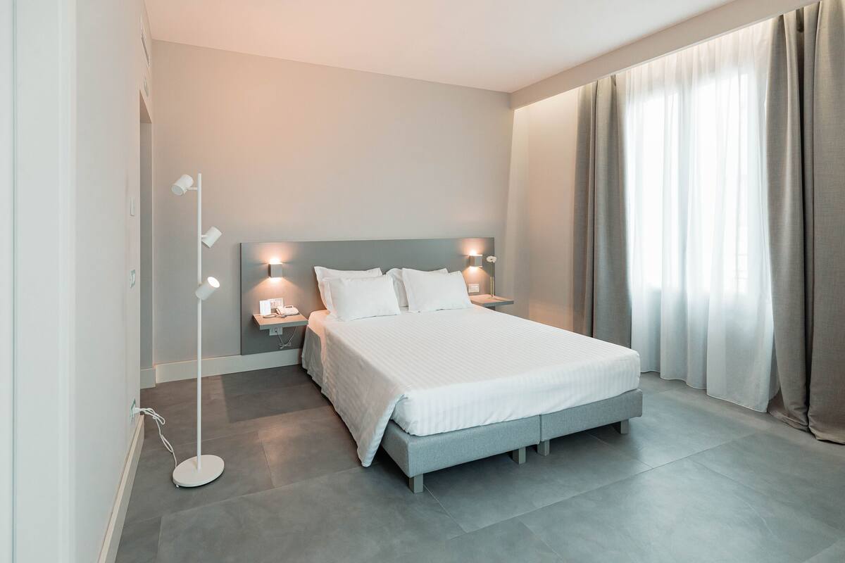 A modern bedroom with a large bed, bedside lamps, and a floor lamp.