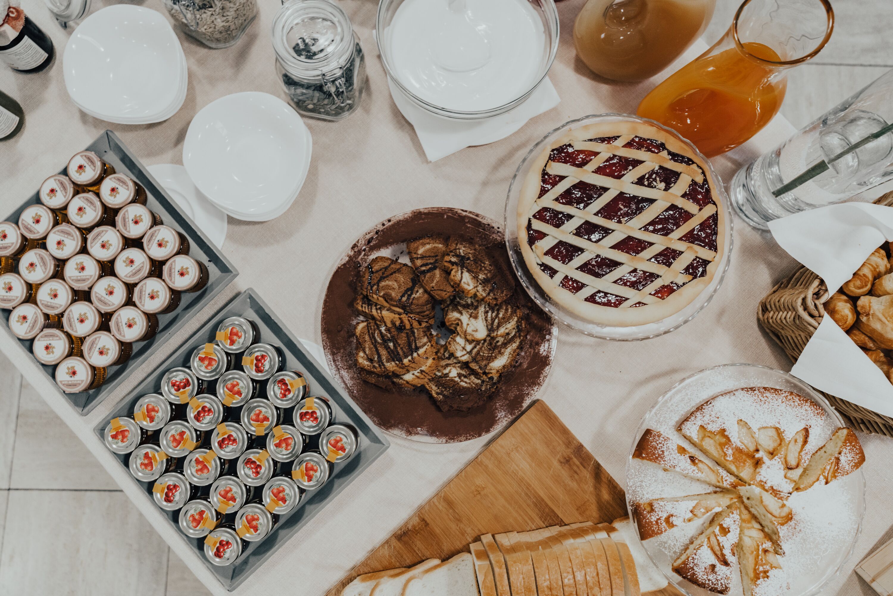 Una mesa con diferentes alimentos, incluyendo tartas, pasteles y frascos de conservas.