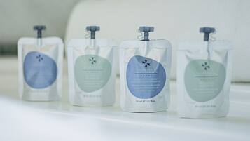 Four toiletry bags on a white surface with a marble wall in the background.