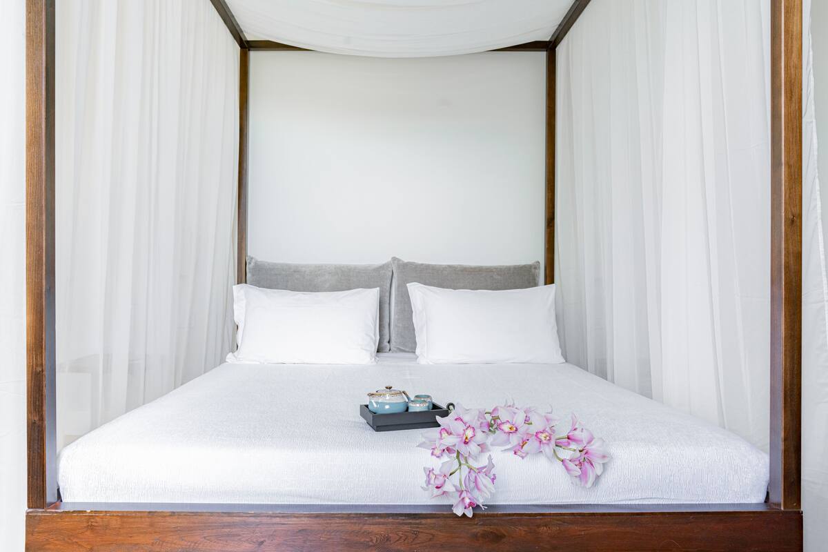 A neatly made bed with white linens, a grey headboard, and a small tray with decorative items.