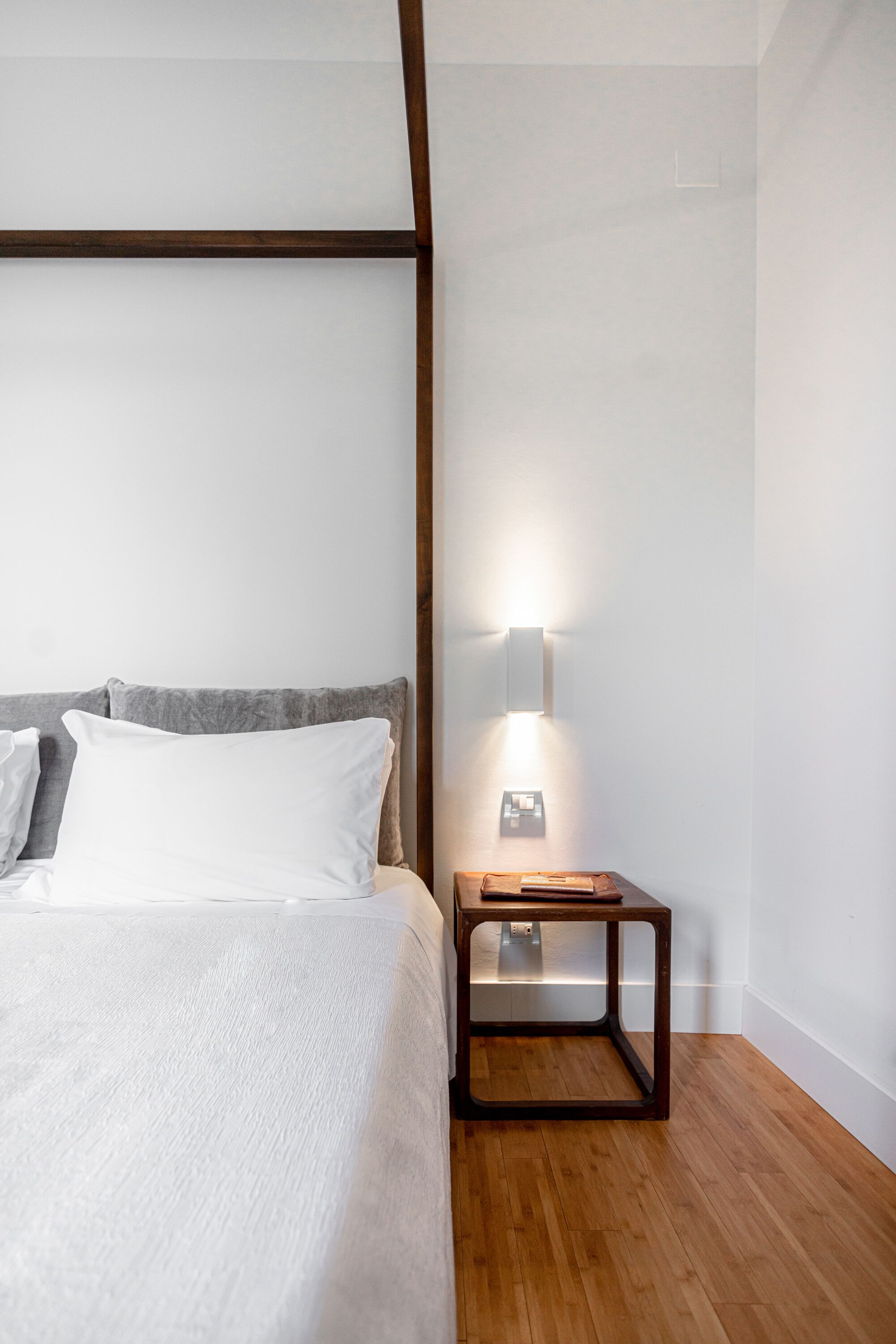 A bedroom with a bed, a nightstand, and a wall-mounted light fixture.