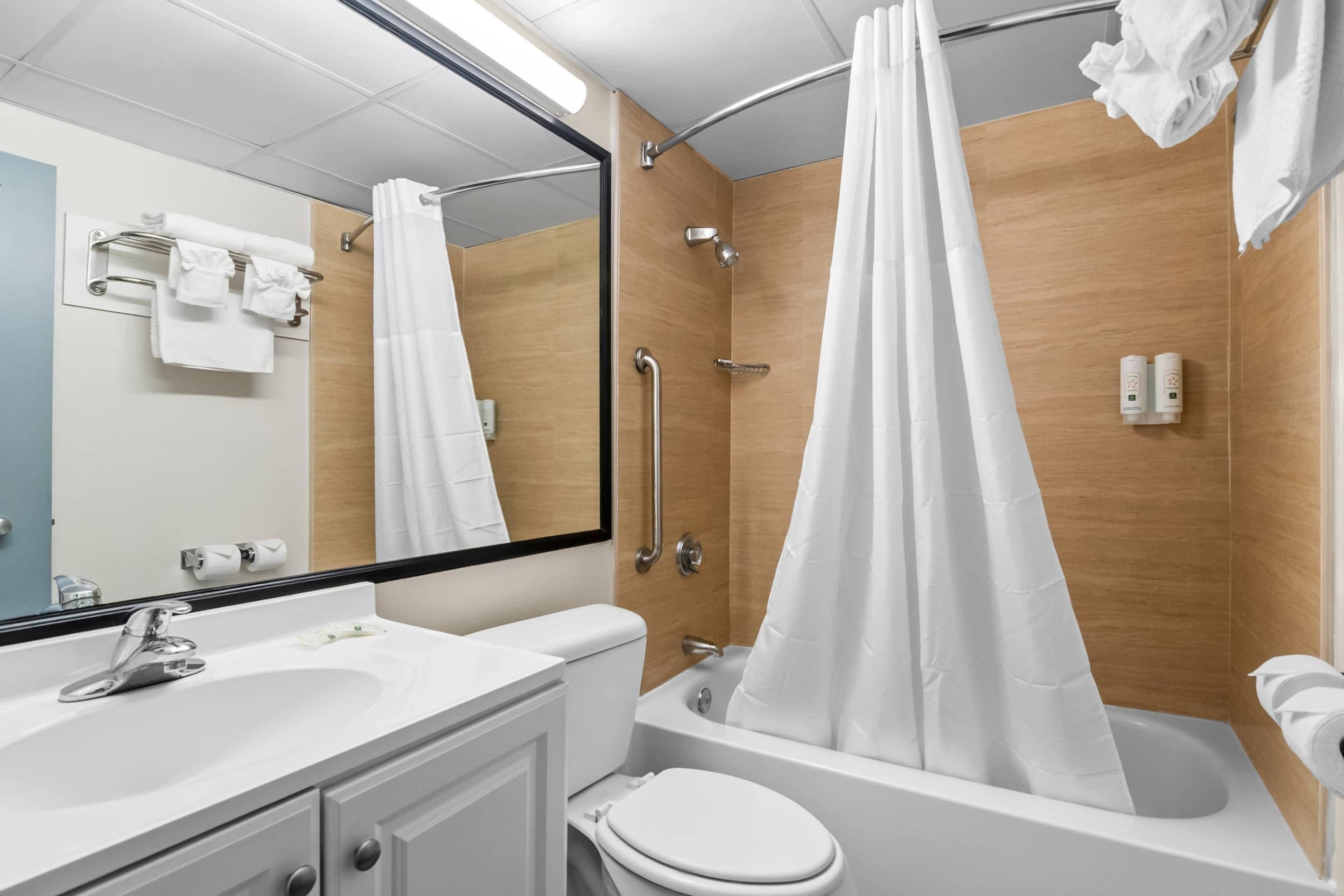Een badkamer met een bad, toilet, wastafel en spiegel.
