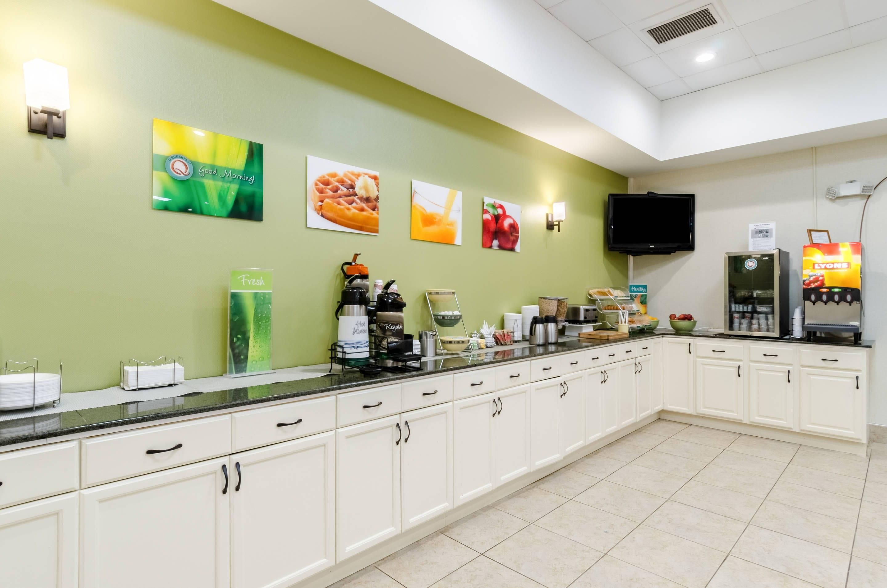 A breakfast bar with a flat-screen TV, a coffee machine, and a refrigerator.