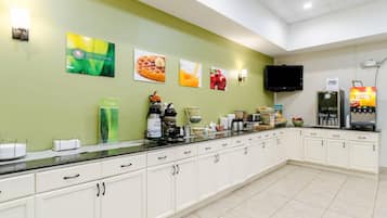A breakfast bar with a flat-screen TV, a coffee machine, and a refrigerator.