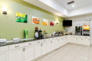Una barra de desayuno con televisión de pantalla plana, cafetera y refrigerador.