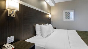 A hotel room with a neatly made bed, a bedside telephone, and wall-mounted lamps.