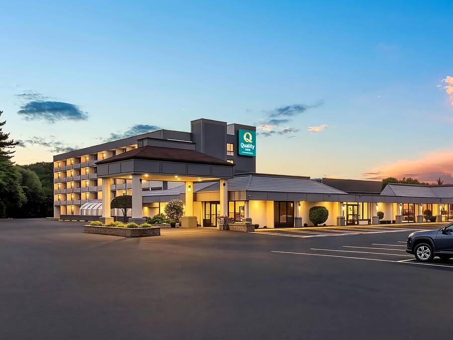 A hotel with a modern design, a parking lot, and a clear sky.