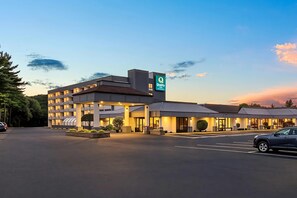 A hotel with a modern design, a parking lot, and a clear sky.