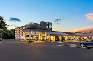 A hotel with a modern design, a parking lot, and a clear sky.