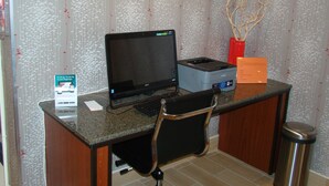 A workspace with a laptop, printer, and keyboard on a desk, a chair, and a trash can. - Quality Inn West Springfield (West Springfield)