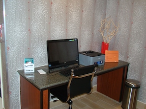 A workspace with a laptop, printer, and keyboard on a desk, a chair, and a trash can. - Quality Inn West Springfield (West Springfield)