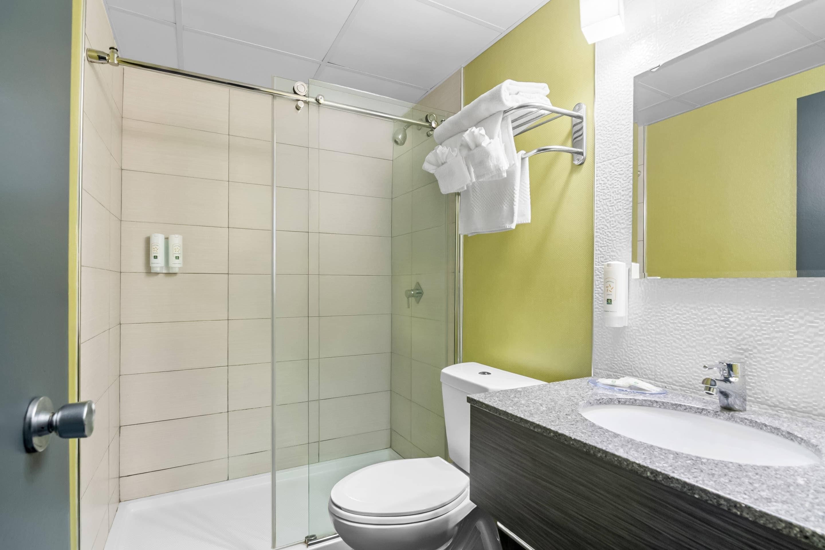 A modern bathroom with a shower, toilet, and sink.