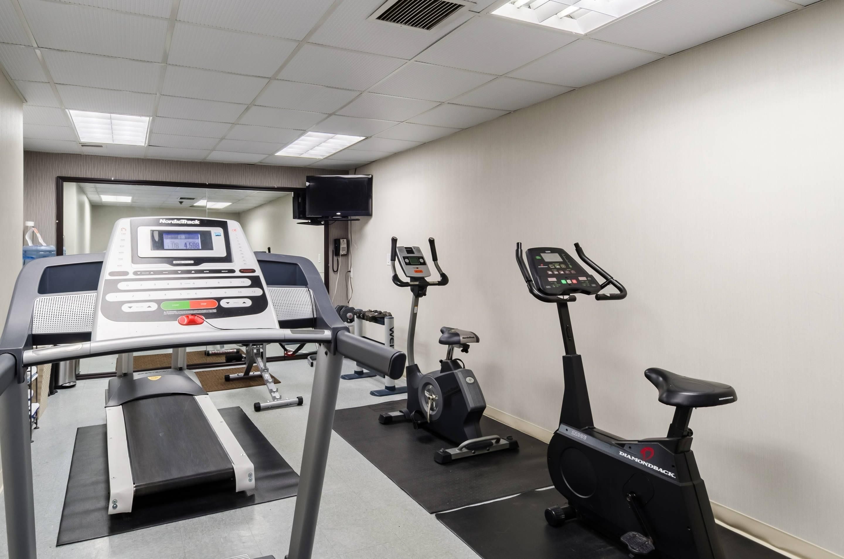 Uma academia com equipamentos de cardio, incluindo esteira, elíptico e bicicleta ergométrica.