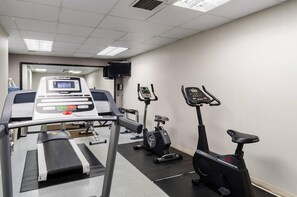 Un gimnasio con equipo cardiovascular, que incluye una caminadora, una elíptica y una bicicleta estática.