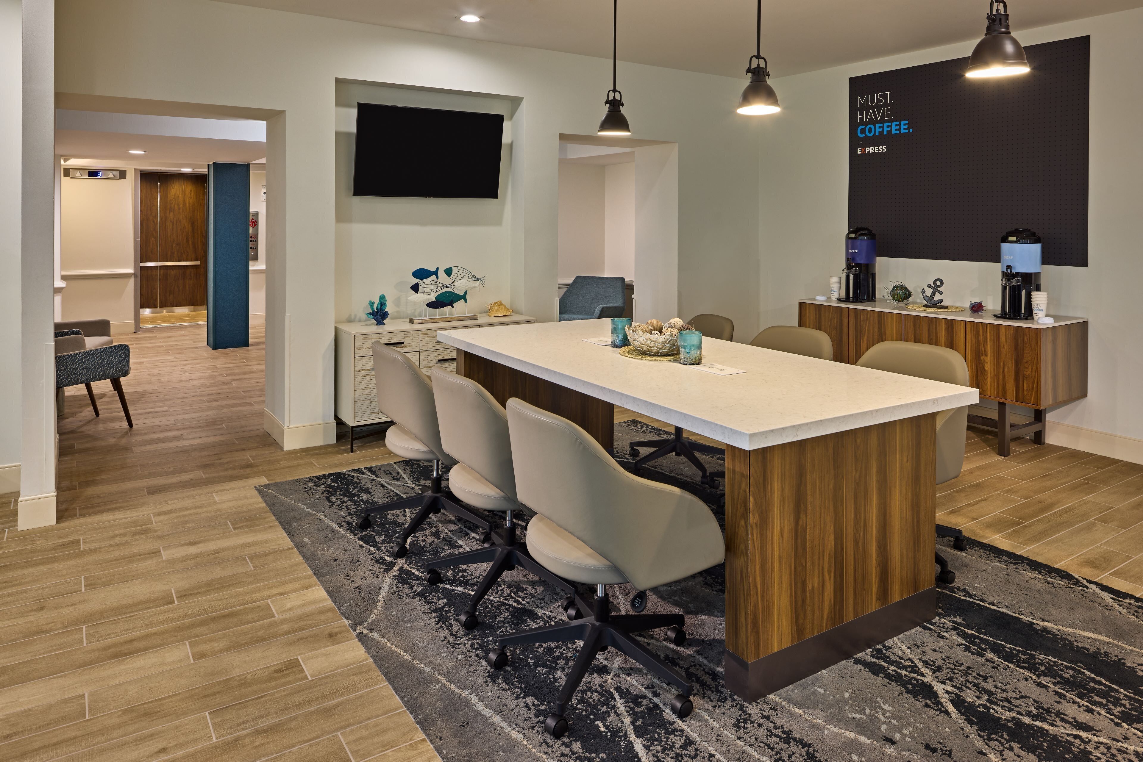 A modern kitchen with a central island, seating area, and a coffee station.