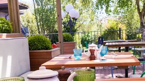 An outdoor patio area with wooden tables and chairs, a lamp post, and potted plants.