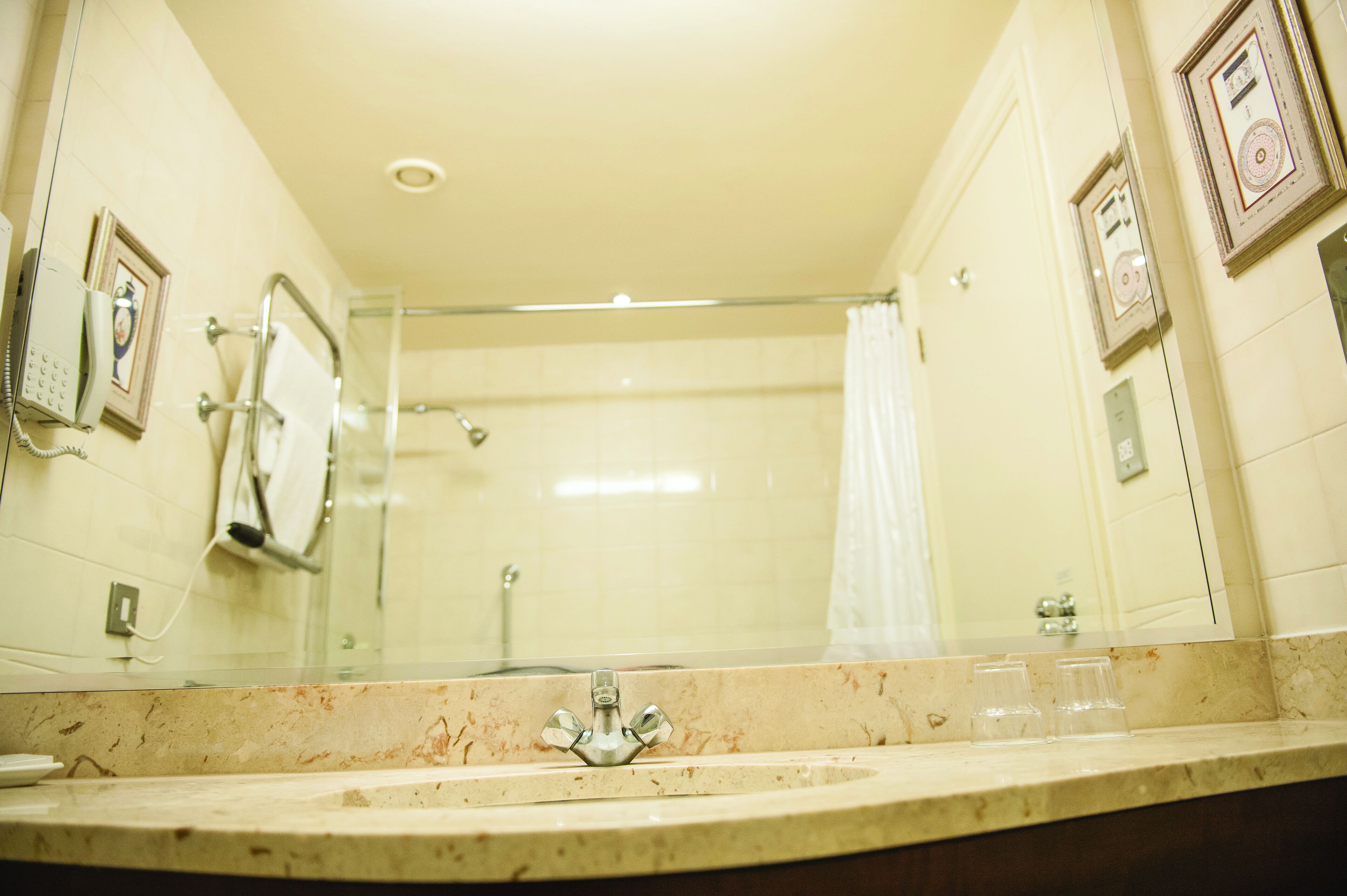 A bathroom with a marble sink, a glass shower enclosure, and framed pictures on the walls.
