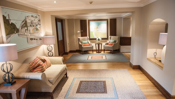 A hotel lobby with a sofa, armchairs, a coffee table, and a rug.