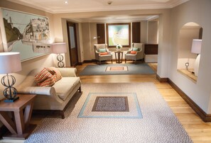 Un hall de hotel con un sofá, sillones, una mesa de centro y una alfombra.