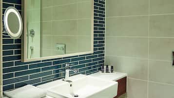 A bathroom with a white sink, mirror, and toilet. It features blue and beige tiles, a wooden vanity, and a towel on the counter.