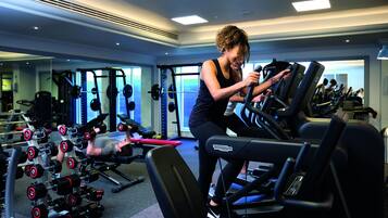 Une salle de sport équipée de tapis de course, d’appareils de musculation et d’haltères.