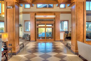 A lobby with a checkered floor, wooden columns, and a glass door with an exit sign.
