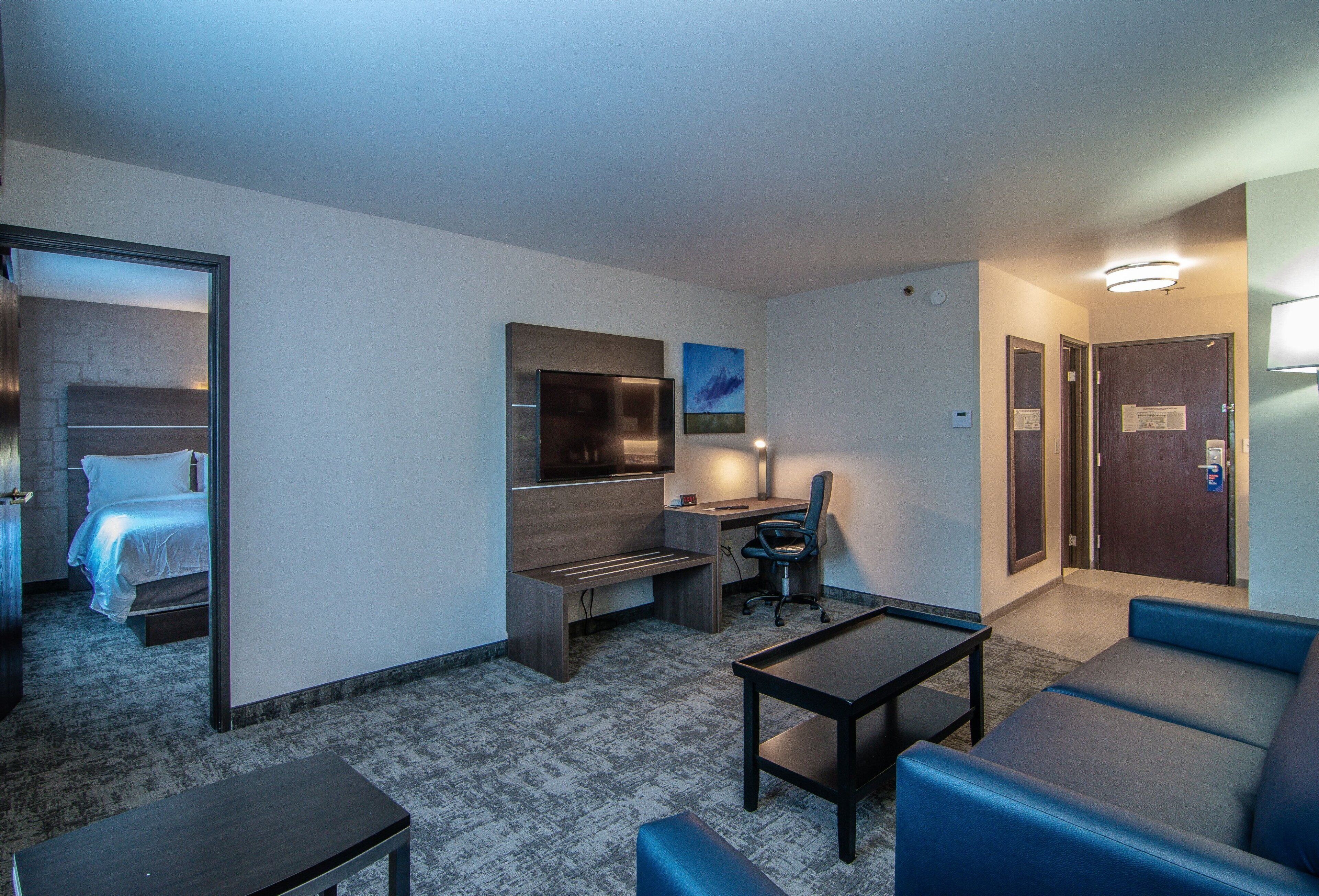 A hotel room with a bed, a desk, a chair, a TV, and a couch.
