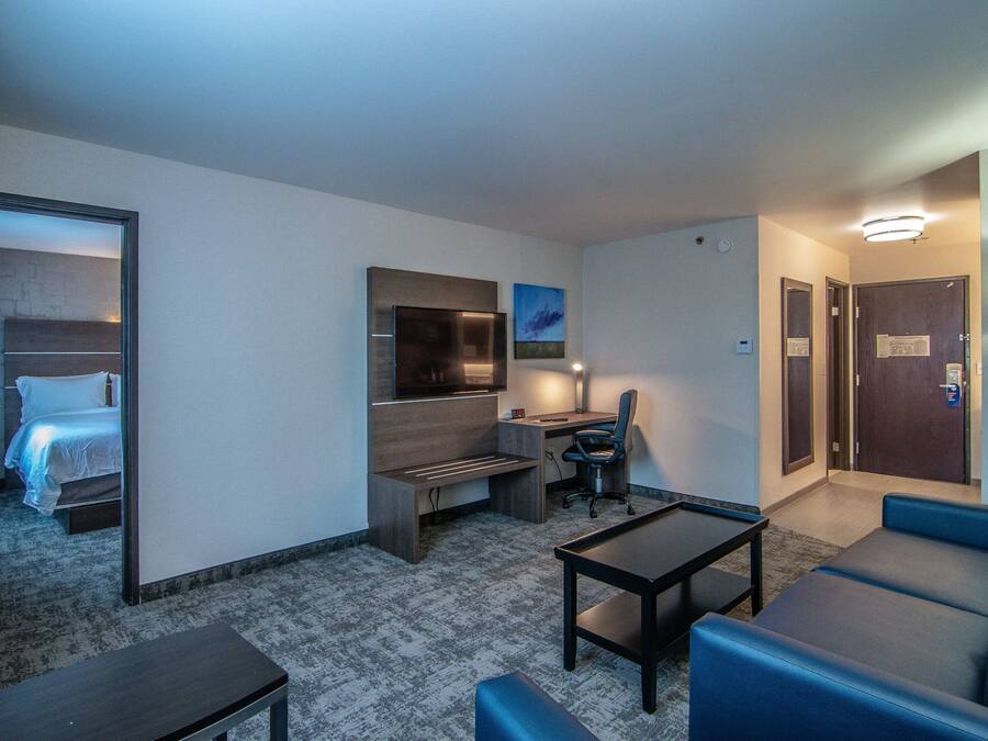 A hotel room with a bed, a desk, a chair, a TV, and a couch.
