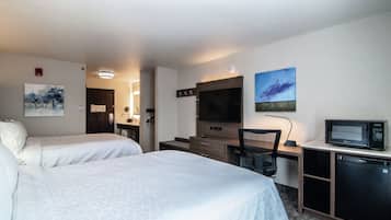 Habitación de hotel con dos camas, un escritorio con computadora, un televisor y un microondas.