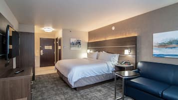 Une chambre d’hôtel avec un lit, une télévision, un bureau, une chaise et un tableau au mur.