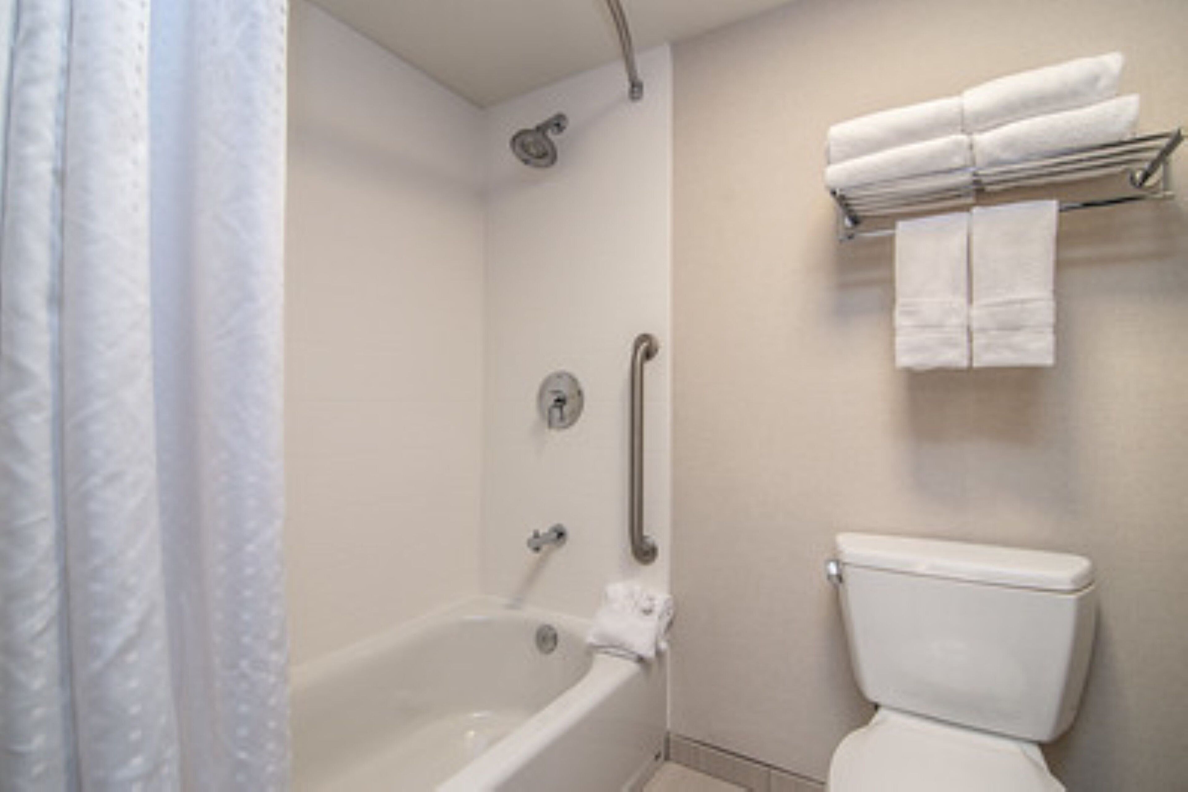 A bathroom with a bathtub, a toilet, and a towel rack with towels.