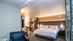 A hotel room with a large bed, a desk, a chair, and a bathroom visible through an open door. - Holiday Inn Express Spokane Downtown by IHG (Spokane)
