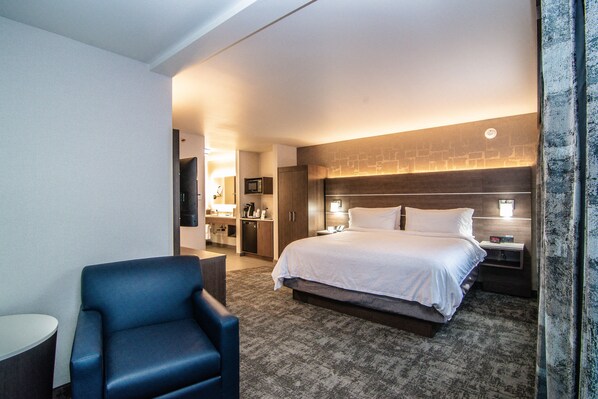 Camera d'albergo con un letto grande, una scrivania, una sedia e un bagno visibile attraverso una porta aperta.
