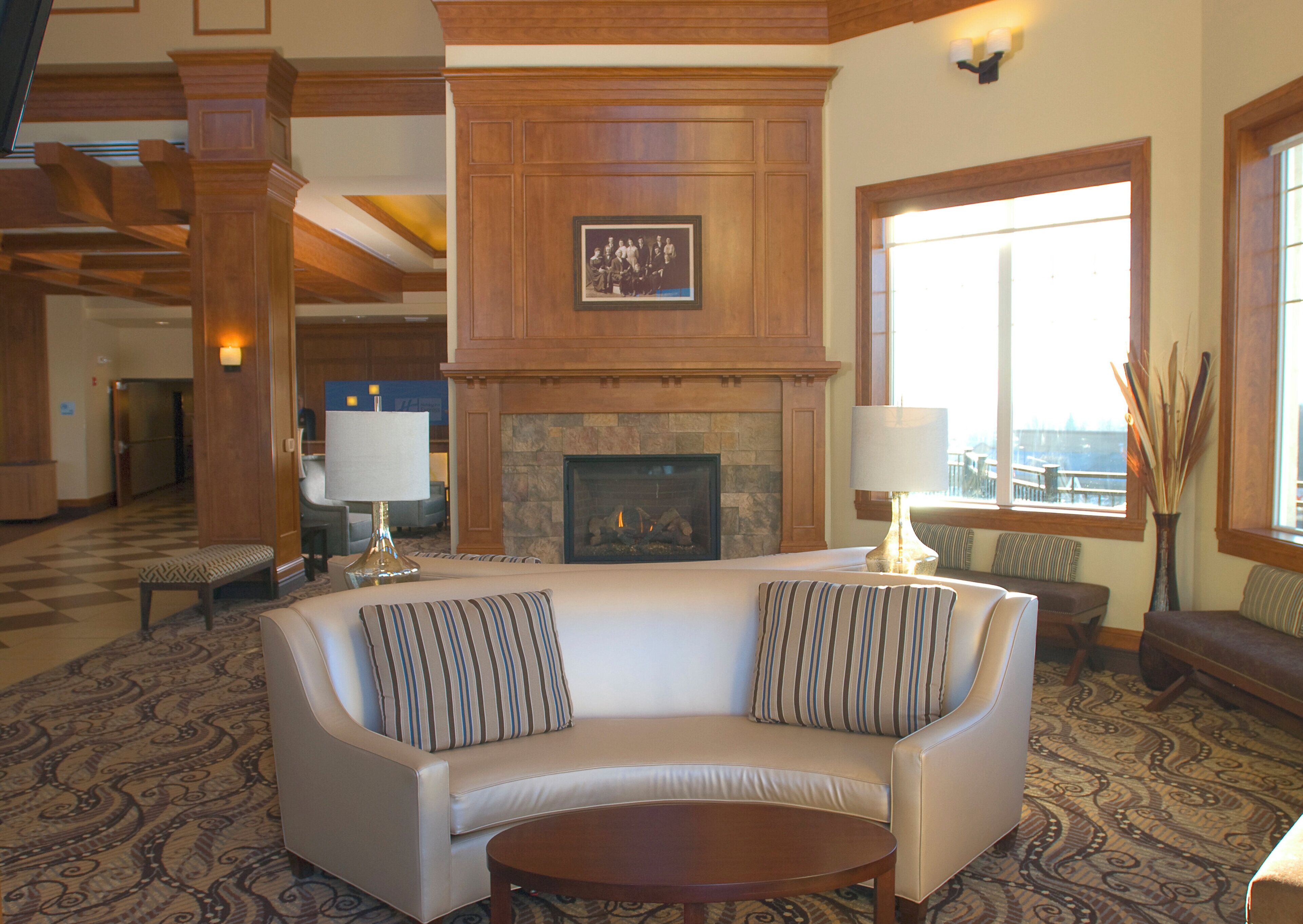A spacious lobby with a fireplace, a large sofa with striped cushions, and a patterned carpet.