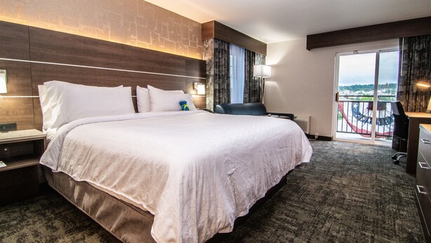 A hotel room with a large bed, a desk, a chair, and a view of the city through the window. - Holiday Inn Express Spokane Downtown by IHG (Spokane)