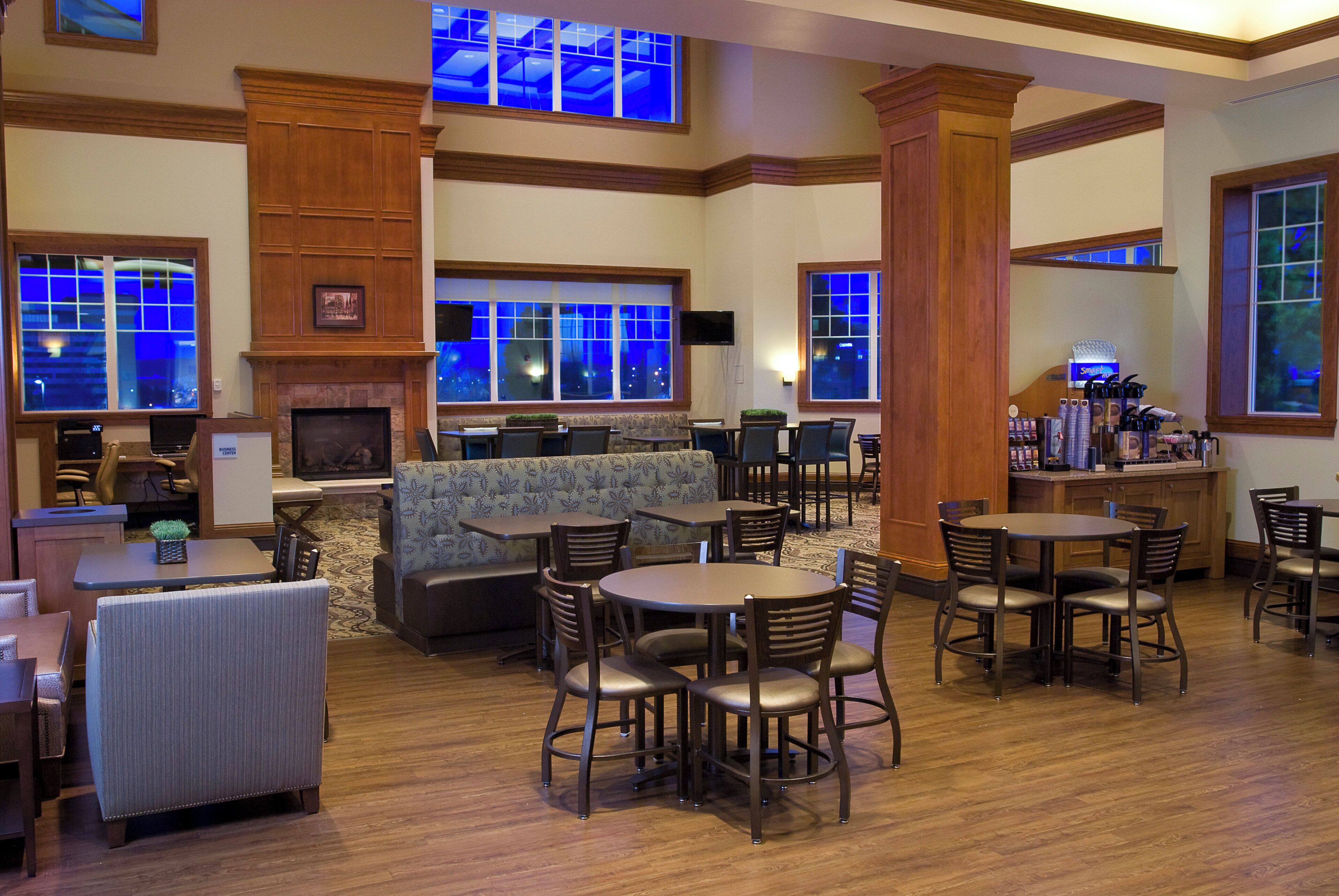 A hotel lobby with a fireplace, seating areas, and a bar.