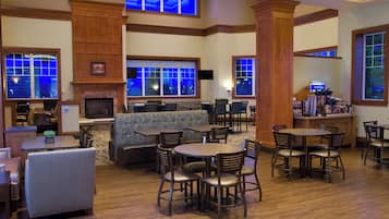 A hotel lobby with a fireplace, seating areas, and a bar.