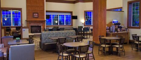 A hotel lobby with a fireplace, seating areas, and a bar.