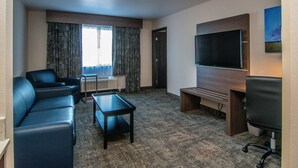 A hotel room with a seating area, a flat-screen TV, a window with curtains, and a carpeted floor. - Holiday Inn Express Spokane Downtown by IHG (Spokane)