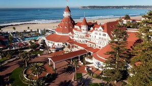 A large hotel with multiple red-roofed buildings, a swimming pool, and a beach view. - Hotel del Coronado, Curio Collection by Hilton (Coronado)